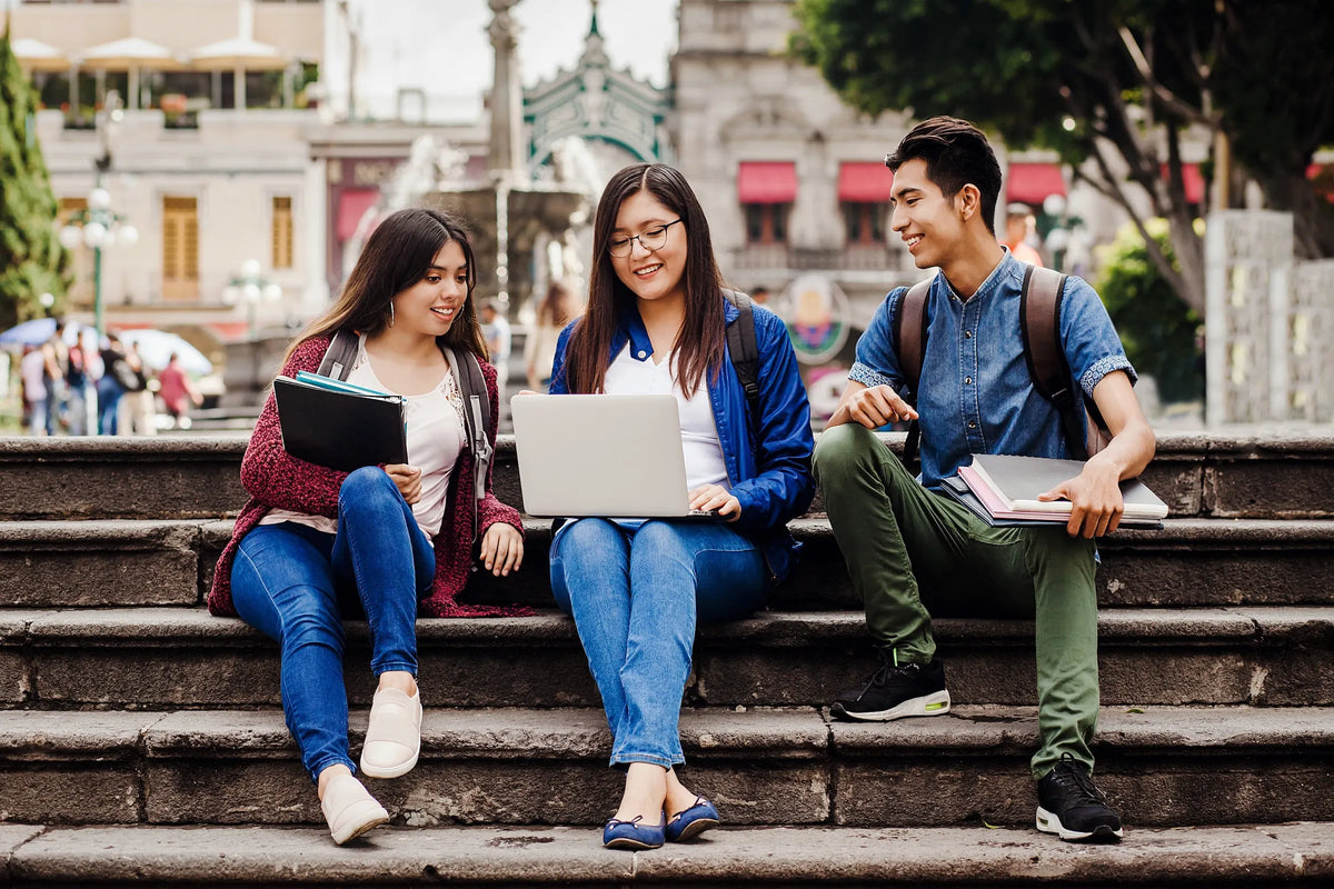 Estudiantes universitarios con laptops sentados en unas escaleras